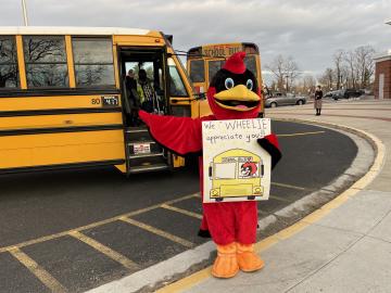Abingdon Cardinal standing in front of school buses with posters showing appreciation for the bus drivers